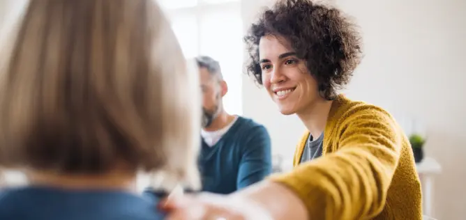 A supportive counselor gently reaches out to a client during a group therapy session, fostering a compassionate and healing environment for mental health and addiction recovery.